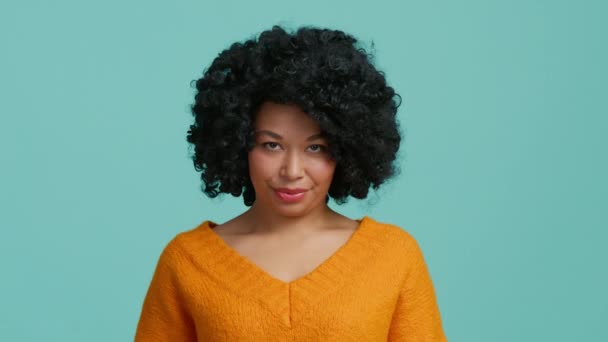 积极微笑的非裔美国人模式同意提供 有非洲式的发型 穿着橙色的 孤立的蓝色背景 脸色苍白 皮肤苍白 点头表示同意的女人说 这是真的 — 图库视频影像