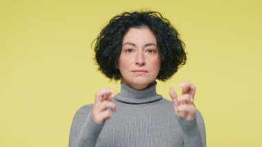 Bana şans dile. Tedirgin Olgun Kadın şans dilemek için şans diliyor. Sarı Stüdyo Arkaplanındaki kameraya bakıyor. 40 'lı yaşlarda Dilek Tutan Kadın Portresi