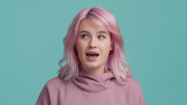 流行のライトピンクの髪の色を持つ20代の若い女性は スタジオで青の背景に隔離された願いを作る 良い何かを請う 言って 交差指でカメラを見てください 人々のライフスタイルコンセプト — ストック動画