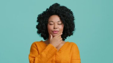 Harika bir fikir. Sevimli Afro-Amerikalı kız işaret parmağını kaldırdı ve harika bir fikir ortaya attı. Kıvırcık saçlı model, pastel mavi arka planda izole edilmiş kameraya bakıyor, kavramı anlıyor.