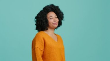 Afro saç stili mutlu bir kız gülümseyip kamerayı işaret ediyor. Afrika kökenli Amerikalı kadın el seçimi gösteriyor. Portre dostu Afrikalı Amerikalı kız 4K