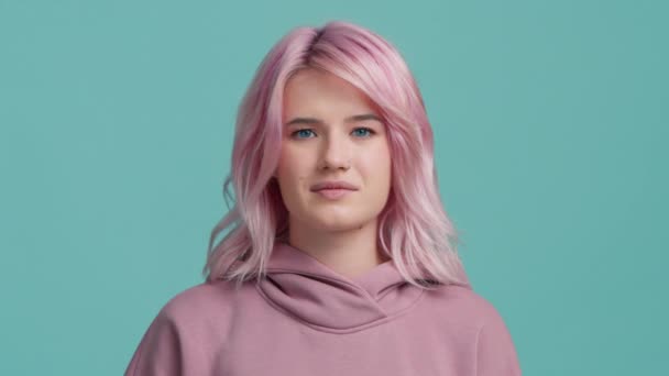 ピンク色の髪の学生少女の肖像が突然首の痛みを感じている 首の筋肉に痛みを伴う色の髪型を持つ疲れた若い女性 スタジオブルーの背景で撮影されたヘルスケアと医療のコンセプト — ストック動画