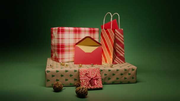 スローモーションエメラルドグリーンの動きの背景にプレゼントを形成する赤いクリスマスギフトボックスのスタック クリスマスグリーティングカードの中に赤い封筒と黄金の色を開いた 愛と家族の概念が撃たれた — ストック動画