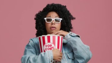 3D TV 'de gerilim filminden dehşete düşmüş ve kontrolsüz bir şekilde patlamış mısır yiyen komik, sevimli Afrikalı Amerikalı genç kadının portresi. Korkak kadın yüksek sesle bağırıyor. Movie Plot Efektlerinden Akıl Uçurma