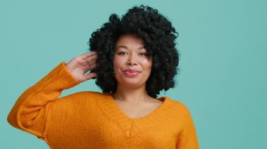 Oyuncu Afro-Amerikan model doğrudan kameraya bakıyor ve kafa hareketlerini göstererek şaka yapıyor. Çok ahlaklı, siyah kıvırcık saçlı, beyaz dişli 4K ile gülen bir kadın.