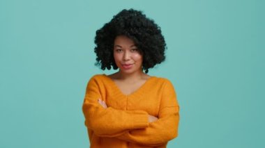 Oyuncu, Afro-Amerikan model, flört eden gözleriyle kameraya bakıyor ve güzel yüzünde gizemli bir gülümseme var. Göğsünde çapraz ellerle ciddi gibi davranan çok ahlaklı kıvırcık kadın.