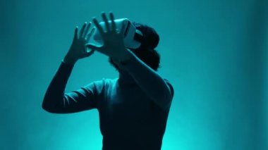 Müstakbel VR Eğitim Teknolojisi Yetişkin Kadın Sanal Gerçeklik Kulaklığını mavi arka planda kullanıyor. Dişi dokunmatik nesneler, sürükleyici bir oyunda. Eğlence Teknolojileri Çeşitliliği Yavaş Hareket Konsepti