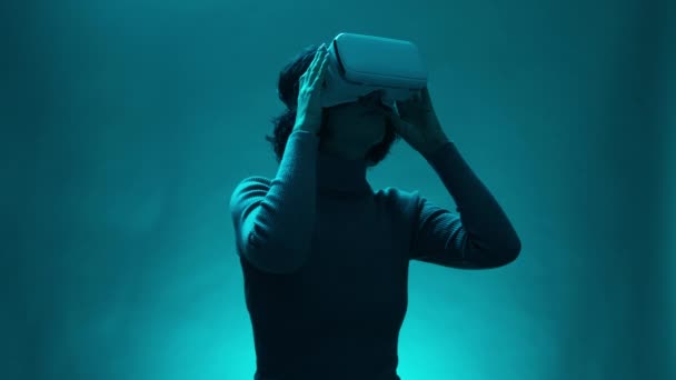 デジタルインタラクティブパフォーマンス 未来のエンターテイメント 技術でVrヘッドセットユーザーと女性モデル 熟女は テールブルーライトの魔法の雰囲気の中で仮想または拡張現実ガラスを使用しています — ストック動画