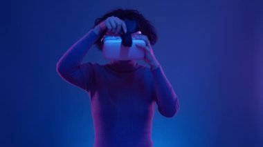 VR gözlüklü siber oyuncu neon fütüristik uzayda sanal gerçeklik oyunu oynuyor. Siberpunk moda oyunları konsepti. Güzel, olgun bir kadın Google kullanıyor ve AR metaverse rüya alemine bakıyor.