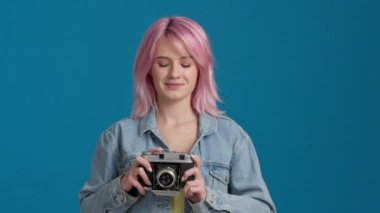 Pembe renk saç stili ve stüdyosunda analog kamera olan neşeli, güzel kız öğrenci portresi. Mutlu genç hippi kadın turist fotoğraf çekiyor. Fotoğraf çeken.