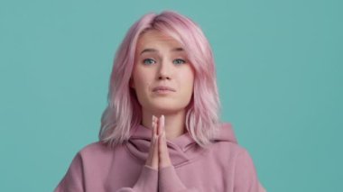 Genç hippiler dua ederken el ele tutuşup mavi arka planda yavaş çekimde izole edilmiş bir dilek diliyorlar. 20 'li yaşlarda, pastel pembe saçlı, pembe kapüşonlu komik bir kadın.