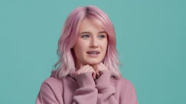 Gergin genç bir kadın panik içinde, endişeli ve kafası karışık. Yirmili yaşlarda, mavi kapüşonlu, mavi kapüşonlu, pastel pembe saçlı, eğlenceli, genç hippi bir öğrencinin portresi.