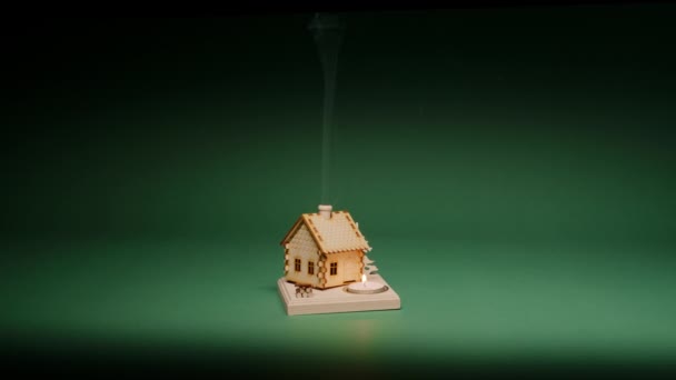 おもちゃの建物の前で燃える煙突と茶筒から煙と小さな木製のログハウスと魔法の夜の背景 緑の背景のクリスマスシーン コピースペーススローモーション Red — ストック動画