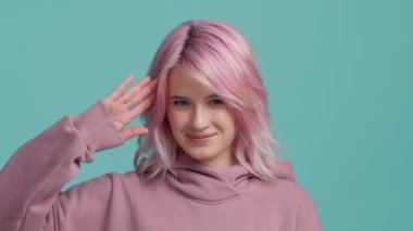 Güzel, gülümseyen, serçe parmaklı, genç bir kız, seni daha sonra renkli yeşil arka planda kamerada görmek istiyor. Evet, efendim. Elinizi başınızın üstüne koyun ve yavaş çekimde 4K yapın.