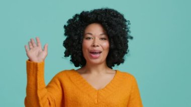 İzole edilmiş arka planda kameraya merhaba diyen bir kadın sosyal uzaklık arkadaşıyla sanal görüşme için arıyor. Genç mutlu Afrikalı Amerikalı karışık ırk hipster video blogcusu kadın web kamerasına el sallıyor.