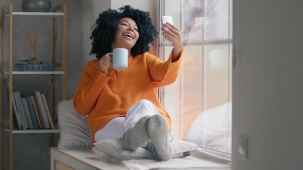 Lykkelig Kvinne Som Drikker Kaffe Foran Telefonkamera Ved Vinduet Pen – stockvideo