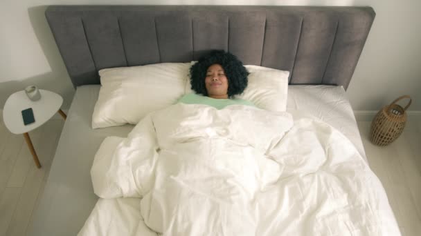 아프리카 미국인 여성이 일어나자마자 침대에 채이른 아침에 카메라 앞에서 위에서 — 비디오