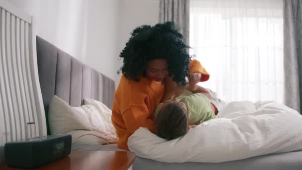 4Kスローモーションでお母さんと子供の優しい瞬間楽しい時間 アフリカ系アメリカ人のママがベッドの上に寝そべっている 笑顔思いやりのある混合レースの母とかわいい子供抱っこ — ストック動画