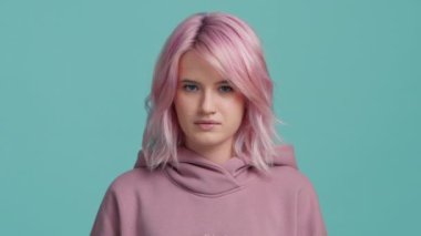 Ağır çekimde moda pastel pembe saç renginde havalı funky kız yüzünü çatık kaşlarıyla sinirlendirdi. Genç hippi kadın kameraya kaşlarını çatarak bakıyor. Portre kızı 4K
