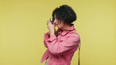 Gülümseyen seyahat blogcusu hayatı, motivasyon macera konsepti. Sarı arka planda pembe ceketli mutlu olgun kadın. 40 'lı yaşlarda bir kadın, özgün film analog kamerasında mükemmel bir görüntü arıyor.