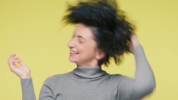 肖像画の豪華な成熟した笑顔の女性の40年代を楽しく踊りを閉じると 短い暗い巻き毛側から側に開発し 黄色の背景に遅い動き 正の感情自由の概念スローモーション — ストック動画