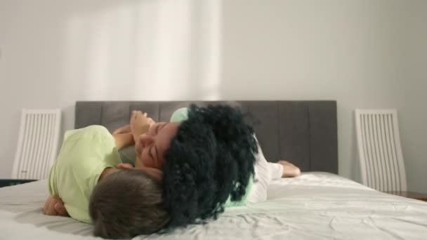 아프리카 미국인 엄마가 귀여운 아들을 간지럽히다니 가족들은 침대에서 긴장을 웃음을 — 비디오
