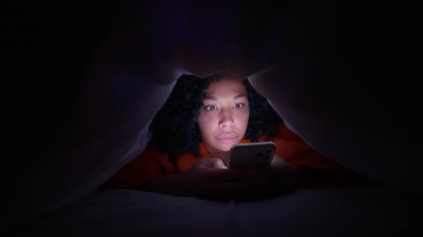 Jovem Afro Americana Deitada Sob Cobertor Com Smartphone Noite Quando — Vídeo de Stock