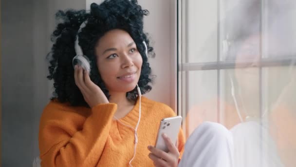 Närbild Porträtt Leende Afroamerikansk Kvinna Hörlurar Med Hjälp Smarttelefon Sitter — Stockvideo