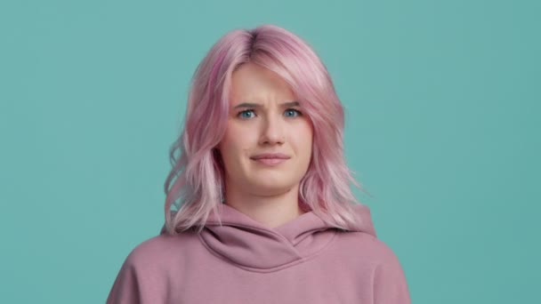 Серйозна Молода Жінка Років Рожевим Волоссям Ізольована Сльозогінному Синьому Фоні — стокове відео