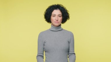 Cunning mature woman with curly hair plotting insidious plan or travel idea. Thinks through details with thoughts boiling in head. Woman 40s make choice. Positive smiling adult woman yellow background