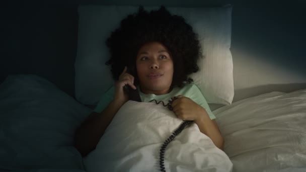 トップダウンビューアフリカ系アメリカ人の女性が積極的に夜にボーイフレンドとロマンチックな関係やゴシップを議論携帯電話でベッドに横たわって表示します 女の子とともにAfro毛のある話で快適なベッド — ストック動画