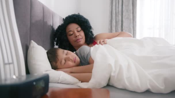 優しいアフリカ系アメリカ人の若いお母さんは 小さな子供にキスを受け入れ 毛布愛らしいかわいい男の子でカバーしています 幸せな愛情のあるお母さん抱っことともに寝たきり就学前の子供の息子でベッドルームにホーム4K — ストック動画