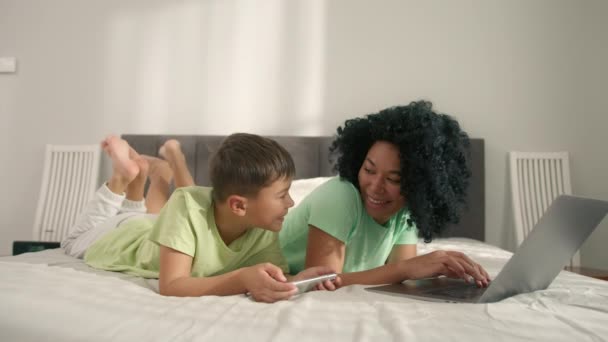 African American Woman Her Preschool Son Lying Bed Using Gadgets — Stockvideo