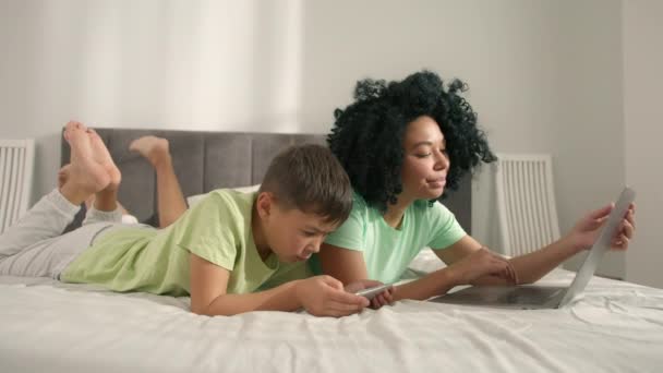 Mom Using Laptop Boy Holding Smartphone Enjoying Online Fun Video — Vídeo de Stock