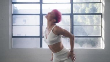 Attractive girl with pink hair flirting looking straight camera. Portrait young woman professional dance trainer performing beautiful modern dance combo with active hands, shoulders and head movements