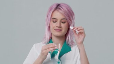 Young physician in hospital uniform put effervescent tablet or aspirin antipyretic pill into glass of water. Vitamin C nutritional supplements in glass, sport medication, medicament drugs prescription