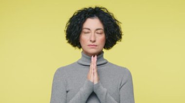 Serious mature woman asking for help, concerned about problem or concentrating mind at work. Religious female worker staying with eyes raised up, put hands in prayer, praying with hope concept 4K