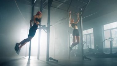 Female athletes pulling their bodies upward for body fitness. Friends working out for muscle strength and fat burning indoors. High quality 4k footage