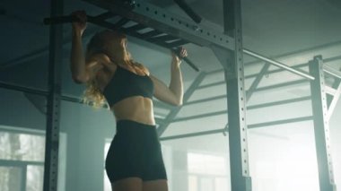 Close-up view of caucasian female athlete pulling up on a crossbar. Strong, determined woman in her 30s working out at the gym. High quality 4k footage