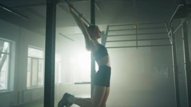 CrossFit sportswoman performing kipping pull-ups. Determined female athlete working out with her own weight at the gym. High quality 4k footage