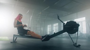 Caucasian female athlete using a pedal exerciser at the gym. Sportswoman improving heart fitness, strengthening her legs and arms. High quality 4k footage