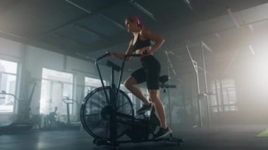 Active, caucasian woman working out on elliptical machine. Female athlete burning calories during intensive cardio workout. High quality 4k footage