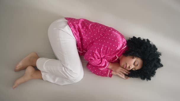 トップ表示色の美しい若い女性は ベッドの上で一日に胎児の位置で居心地の良い睡眠 縦画面方向ビデオ9 16の穏やかなですカールアップアフリカ系アメリカ人女性でファンシーPajama夢の昼寝 — ストック動画
