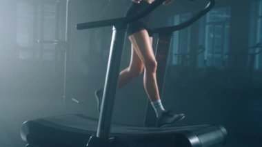 Beautiful, active female athlete using a treadmill device for a cardiovascular workout. Close-up view of sporty, caucasian woman jogging indoors. High quality 4k footage