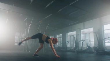 Close-up shot of an active, pink-haired athlete strengthening her muscles at the gym studio. Woman supporting the body in a stable, inverted vertical position. High quality 4k footage