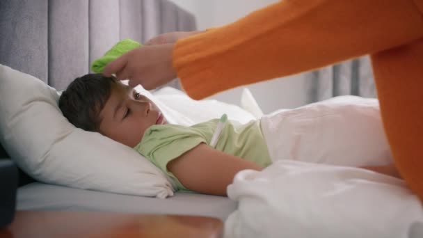 Занепокоєна Мати Торкається Свого Хворого Маленького Сина Лежачи Ліжку Рушником — стокове відео