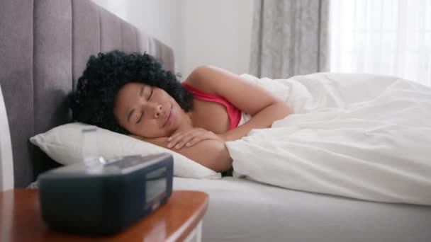 若い陽気なアフリカ系アメリカ人の女性がベッドで目を覚ます デジタルアラームをオフにし ストレッチ 立ち上がり 午前中に寝室を残します 美しい色感覚の女性は夜の睡眠後に活性化 — ストック動画
