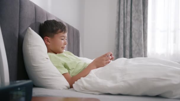 Mixed Race Boy Playing Mobile Game Smartphone Bed Preschooler Playing — Stock video
