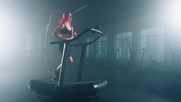 ジムスタジオのトレッドミル装置を使用してピンク色の髪の女の子 心血管のワークアウトを実行しながら 健康とフィット滞在女性 高品質4K映像 — ストック動画