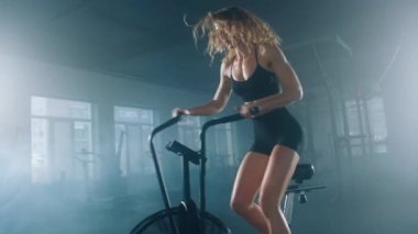 Close-up shot of a sportswoman during an intensive cardiovascular training. Side view of female athlete using an elliptical machine in gym studio. High quality 4k footage